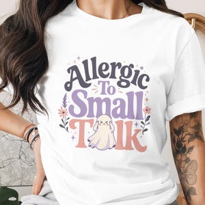 T-shirt with text "Allergic To Small Talk" and a ghost graphic.