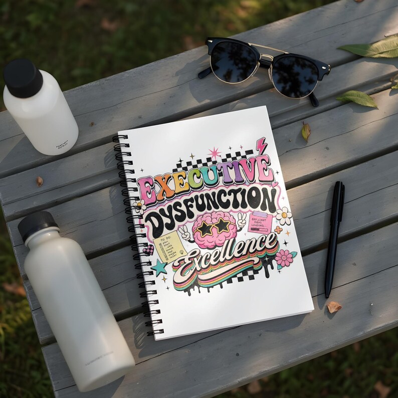 Spiral notebook with "Executive Dysfunction Excellence" and cartoon brain.