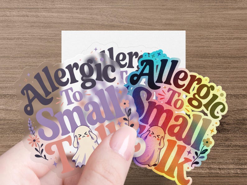 Hand holding clear stickers with "Allergic To Small Talk" text and cartoon ghosts.
