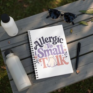 Spiral notebook with "Allergic To Small Talk" text and a ghost illustration.