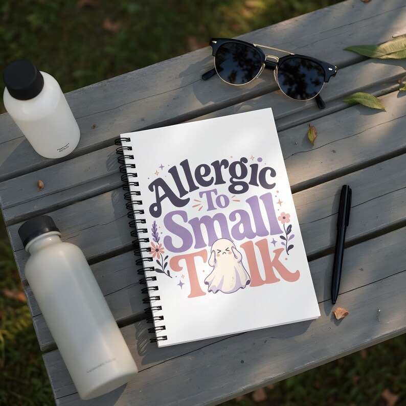 Spiral notebook with "Allergic To Small Talk" text and a ghost illustration.