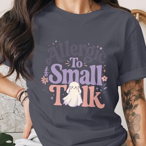T-shirt with graphic: "Allergic To Small Talk" and a sad ghost.