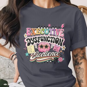 T-shirt with "Executive Dysfunction Excellence" text and colorful graphics.