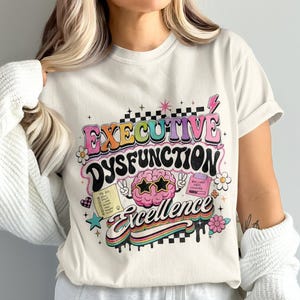 Cream t-shirt with "Executive Dysfunction Excellence" graphic featuring a brain and checklist.