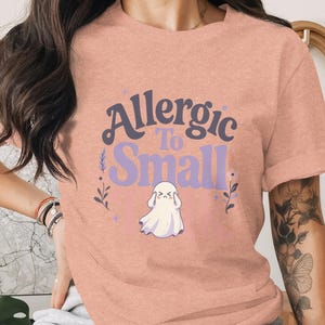 Peach t-shirt with "Allergic To Small Talk" ghost graphic.