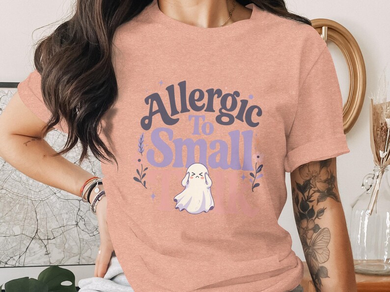 Peach t-shirt with "Allergic To Small Talk" ghost graphic.