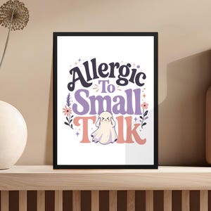"Allergic To Small Talk" text with a ghost and floral design on a framed print.