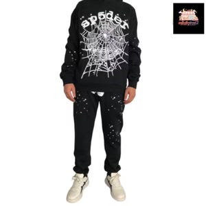 May include: Black hoodie and sweatpants set with a white spider web design and the word "spider" in a stylized font. The sweatpants and hoodie have white star-like accents. The set is paired with white sneakers.