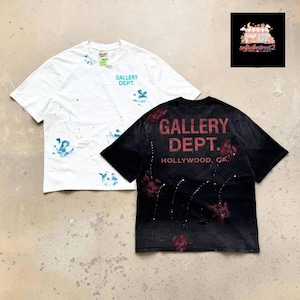 Puede incluir: Una camiseta blanca de manga corta con salpicaduras de pintura azul y el texto GALLERY DEPT. en turquesa, junto a una camiseta negra de manga corta con salpicaduras rojas y el texto GALLERY DEPT. HOLLYWOOD, CA. en una fuente roja desgastada.