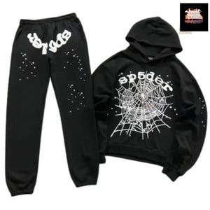 May include: Black sweatsuit set featuring a hooded sweatshirt and matching sweatpants. The sweatshirt displays a white spiderweb design with the word "spider" above it. The sweatpants have the word "spider" in white on the left leg and white star-like accents.