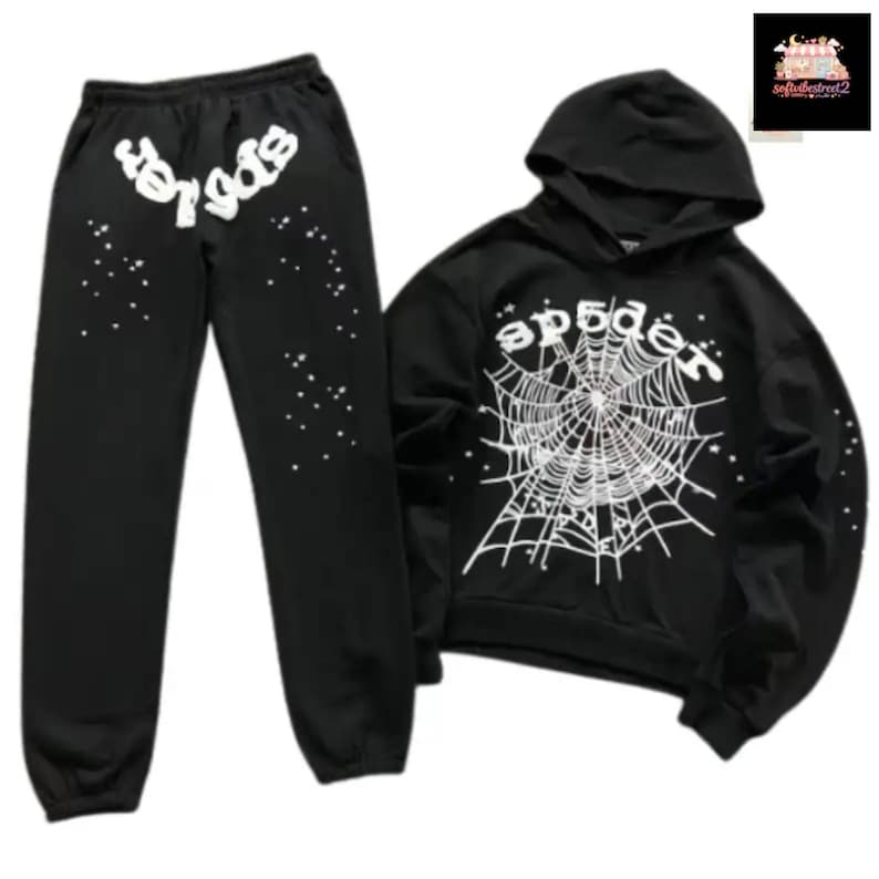 May include: Black sweatsuit set featuring a hooded sweatshirt and matching sweatpants. The sweatshirt displays a white spiderweb design with the word "spider" above it. The sweatpants have the word "spider" in white on the left leg and white star-like accents.