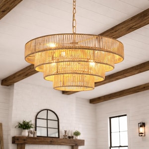 May include: A tiered, round chandelier with a woven, natural fiber design. The light fixture has multiple tiers, each with a warm, golden glow. It hangs from a gold chain and is suspended from a white ceiling with exposed wooden beams.