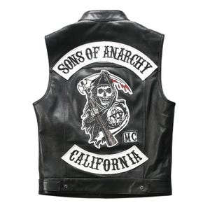 Könnte beinhalten: Eine schwarze Lederweste mit einem großen Rückenaufnäher, der einen Sensenmann mit Gewehr und Sense zeigt. Der Aufnäher enthält den Text SONS OF ANARCHY oben, CALIFORNIA unten und einen kleinen MC-Aufnäher auf der rechten Seite des Motivs.