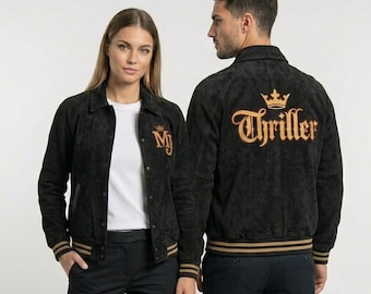 May include: Black suede jacket with gold embroidered "MJ" on the front and "Thriller" on the back. The jacket has a button-up front, a collar, and gold stripes on the cuffs and hem. The jacket is worn by two people.