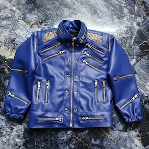May include: A blue jacket featuring a high collar, long sleeves with elastic cuffs, and a front zipper closure. The garment is adorned with multiple gold-toned zippers across the chest and sleeves, along with metallic studs and textured panels.