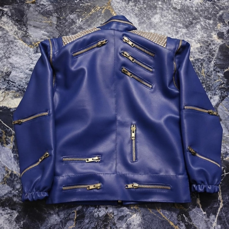 May include: A royal blue jacket featuring multiple silver-toned metal zippers across the front, sleeves, and shoulders. The upper back and shoulder areas are adorned with a dense pattern of small, reflective silver studs in a grid arrangement.