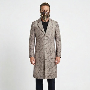 Pode incluir: Um casaco comprido bege com um padrão de pele de cobra. O casaco é usado sobre uma camisa preta e calças escuras. Uma máscara de estilo steampunk com detalhes em castanho e dourado cobre o rosto.