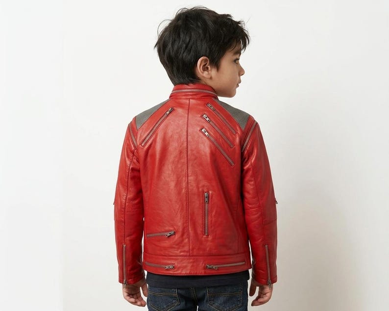 May include: A bright red jacket featuring a stand-up collar, long sleeves, and multiple silver-toned metal zippers placed diagonally and vertically across the back and shoulders. The upper back panel has a textured grey fabric detail.