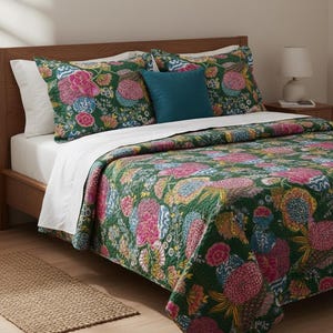 May include: A bed with a green floral quilt and matching pillow shams. The quilt features large pink, yellow, and blue flowers on a dark green background. A teal pillow adds a pop of color. The bed frame is made of wood.