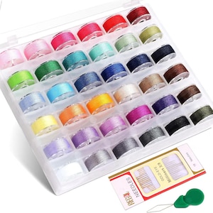 May include: A clear plastic sewing box filled with colorful thread spools in various shades of red, pink, green, blue, and more. Includes a pack of needles and a green needle threader. Ideal for sewing and crafting projects.
