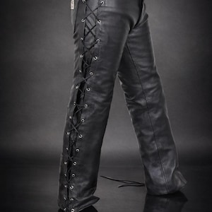May include: Black leather pants with lace-up detailing on the sides. The pants have a classic five-pocket design and a belt loop. The leather appears to be smooth and has a slight sheen. The pants are designed with a bootcut leg opening.