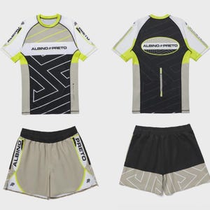 May include: A set of athletic apparel, including a short-sleeved shirt and shorts. The shirt is white, gray, and black with a geometric design and the text "ALBINO & PRETO". The shorts are tan and black with matching accents.