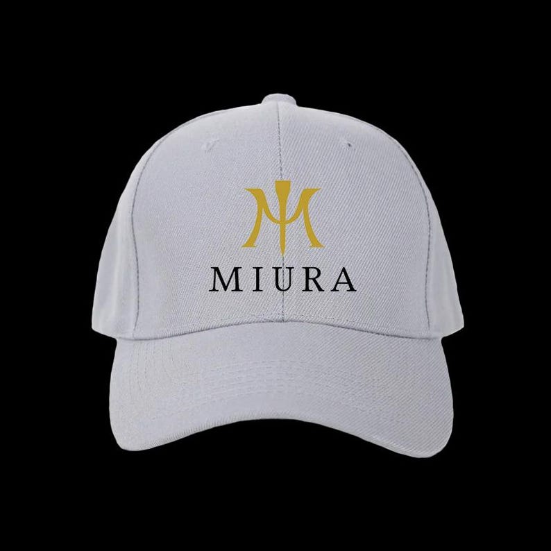 May include: A light gray baseball cap with a curved brim. The cap features a gold emblem and the word "MIURA" in black, centered on the front. The background is solid black.