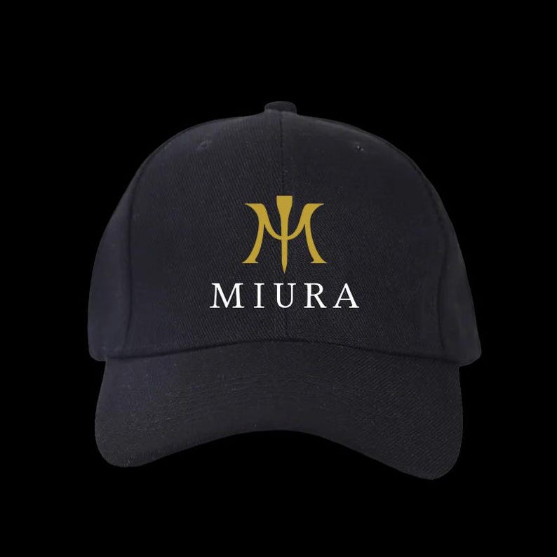 May include: Black baseball cap with a curved brim. The cap features a gold emblem above the white word "MIURA". The emblem is a stylized "M" with a vertical line through the center. The cap is made of a durable fabric.
