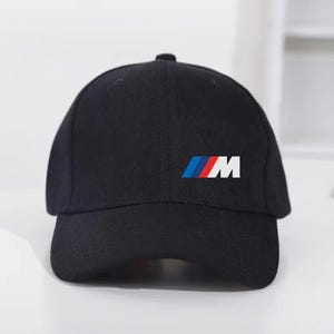 May include: Black baseball cap with the BMW logo on the front. The logo features blue, red, and white stripes with the letter "M". The cap is made of a durable fabric and has a curved brim.