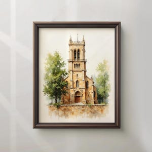 May include: A framed watercolour print depicting a church with a tall spire and arched windows. The church is a light tan colour, surrounded by green trees. The artwork is in a dark brown frame.