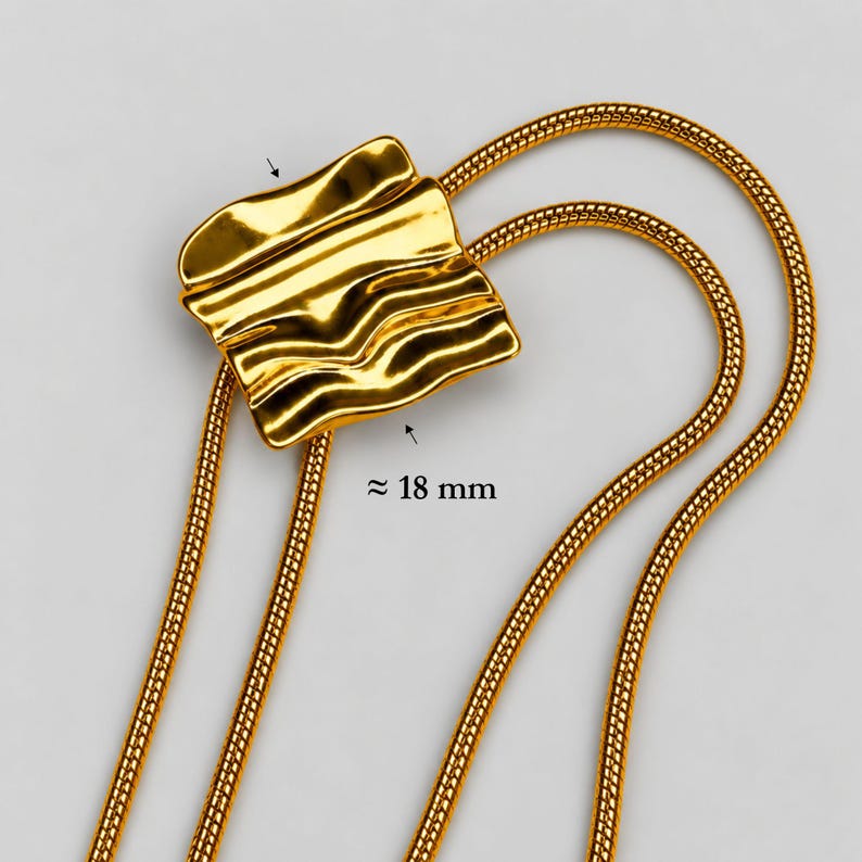 Detailed close-up of the sculptural slider on a gold bolo tie lariat necklace, measuring approximately 18 mm wide. The polished organic wave design sits over the flexible snake chain, showing the distinctive adjustable construction of this statement Y necklace. Macro product photography highlights the smooth reflective gold finish and contemporary design of the long gold necklace.