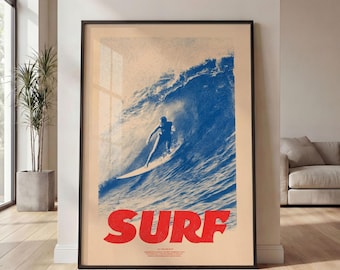May include: A framed wall art print featuring a blue and cream-colored graphic of a surfer riding a large wave. The word SURF is printed in large, bold red letters at the bottom of the print, with smaller text underneath the main title.