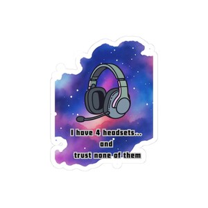 May include: A sticker featuring a pair of grey gaming headphones with a microphone against a vibrant purple and blue galaxy background with white stars. The text reads: I have 4 headsets... and trust none of them in a bold, dark font.
