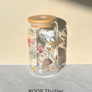 May include: A clear glass tumbler with a wooden lid, decorated with crime scene-themed graphics. The design includes a handprint, footprints, and a detective hat. The text "#008 Thriller" is at the bottom.