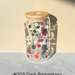 May include: A clear glass tumbler with a bamboo lid, decorated with gothic-themed stickers. The stickers include a skull, roses, a dragon, and a book. The text "#005 Dark Romantasy" is printed at the bottom of the glass.