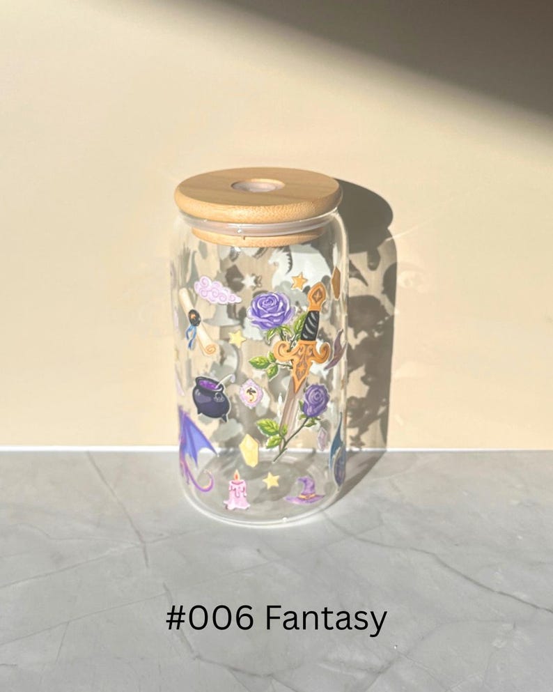 May include: A clear glass tumbler with a wooden lid, decorated with fantasy-themed illustrations. The design includes purple roses, a sword, a witch's hat, and a cauldron. The text "#006 Fantasy" is printed at the bottom.