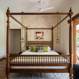 May include: A wooden four-poster bed with a spindle headboard and footboard, featuring a white mattress, two green pillows, and a patterned central cushion. The bed is positioned against a textured stone wall with a framed painting of a cow.