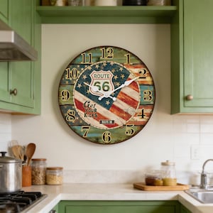 Puede incluir: Un reloj de pared redondo con un diseño de la Ruta 56. La esfera del reloj presenta la bandera estadounidense con las palabras "Route 56" y "Get Your Kicks". El reloj tiene un aspecto vintage desgastado con números y manecillas negras.