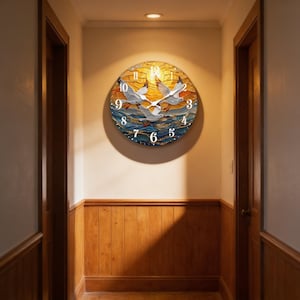 May include: A round wall clock with a seascape design. The clock face features a sunset scene with seagulls in flight over the ocean. The clock has white numerals and hands, and is mounted on a beige wall.