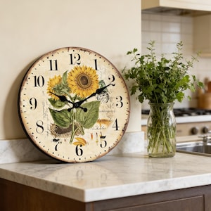 May include: A round wall clock with a vintage design, featuring sunflowers and botanical illustrations. The clock face has black numerals and hands, with a distressed, aged appearance. The clock is set against a neutral background, with a vase of greenery in the background.