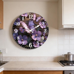 May include: Round wall clock featuring a butterfly and floral design. The clock face has a wooden background with purple flowers and butterflies. The clock hands are white, and the numbers are in a classic font.