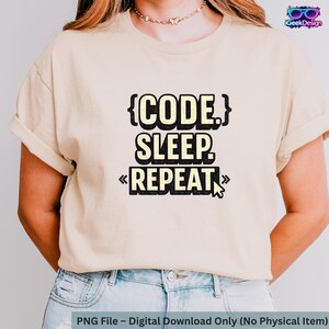 Puede incluir: Camiseta beige con el texto "CODE. SLEEP. REPEAT." en blanco y negro, con un gráfico de cursor de ratón. La camiseta es una descarga digital, sin artículo físico.