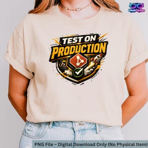 Peut inclure: T-shirt beige avec l'inscription "TEST ON PRODUCTION" dans un design coloré. Le graphisme comprend une fusée et d'autres symboles technologiques. Le bas de l'image indique qu'il s'agit d'un téléchargement numérique, pas d'un article physique.
