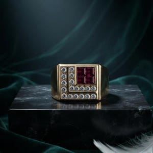 Könnte beinhalten: Ein Goldring mit quadratischem Kopf, der ein tiefrotes Edelsteincluster in einem Quadranten aufweist, umrandet von einer L-förmigen Anordnung kleiner, runder, klarer weißer Diamanten, die sich entlang der Seite und Unterseite der Steine erstrecken.