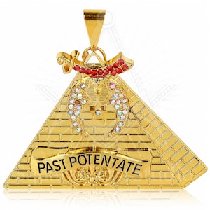 以下が含まれることがあります： 「PAST POTENTATE」の文字が入ったバナーが付いた、ピラミッドデザインのゴールドカラーのペンダント。 赤と虹色のクリスタルのアクセントと装飾的なトップが特徴です。