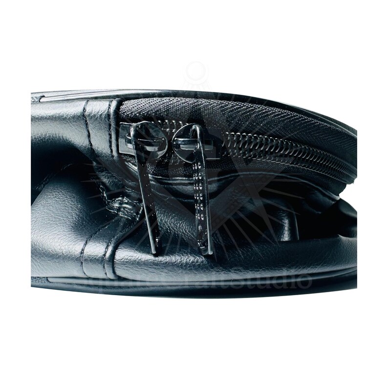 May include: Close-up of a black leather bag with a zipper closure. The bag has a shiny, textured surface and two metal zipper pulls. The zipper runs along the top of the bag.