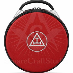 May include: A circular red case with a black handle and zip. It features a white embroidered emblem within a circle, set against a textured background. The handle is black and the case has silver accents.
