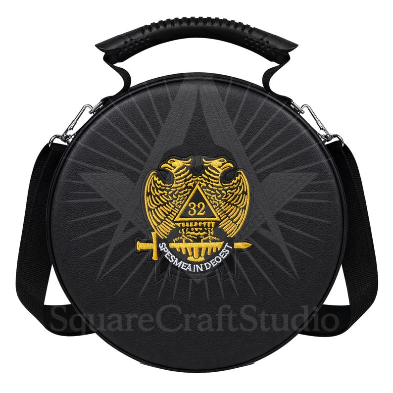 May include: Black round bag with a handle and shoulder strap. The bag features a gold emblem with two eagles, a triangle, and the text "SPES MEA IN DEO EST". The text "SquareCraftStudio" is at the bottom.