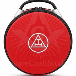 May include: A circular red case with a black zip and handle. The case displays a white emblem within a circle, featuring a stylized 'A' and 'T' design. It has a black handle and silver accents.