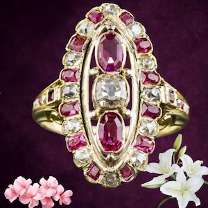 May include: A gold ring featuring an oval design with a central row of three gemstones: two oval rubies and a square diamond. The ring is further adorned with smaller rubies and diamonds, set in a gold band.